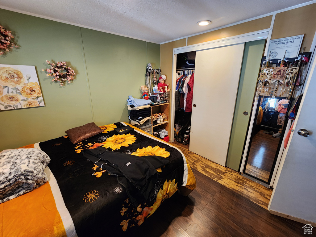 Bedroom with wood finished floors, a closet, and ornamental molding