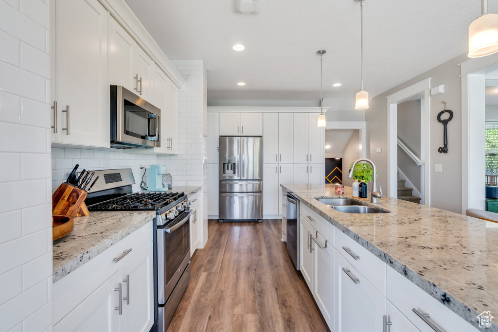 Kitchen with stainless steel appliances, dark wood-type flooring, tasteful backsplash, white cabinetry, and light stone countertops