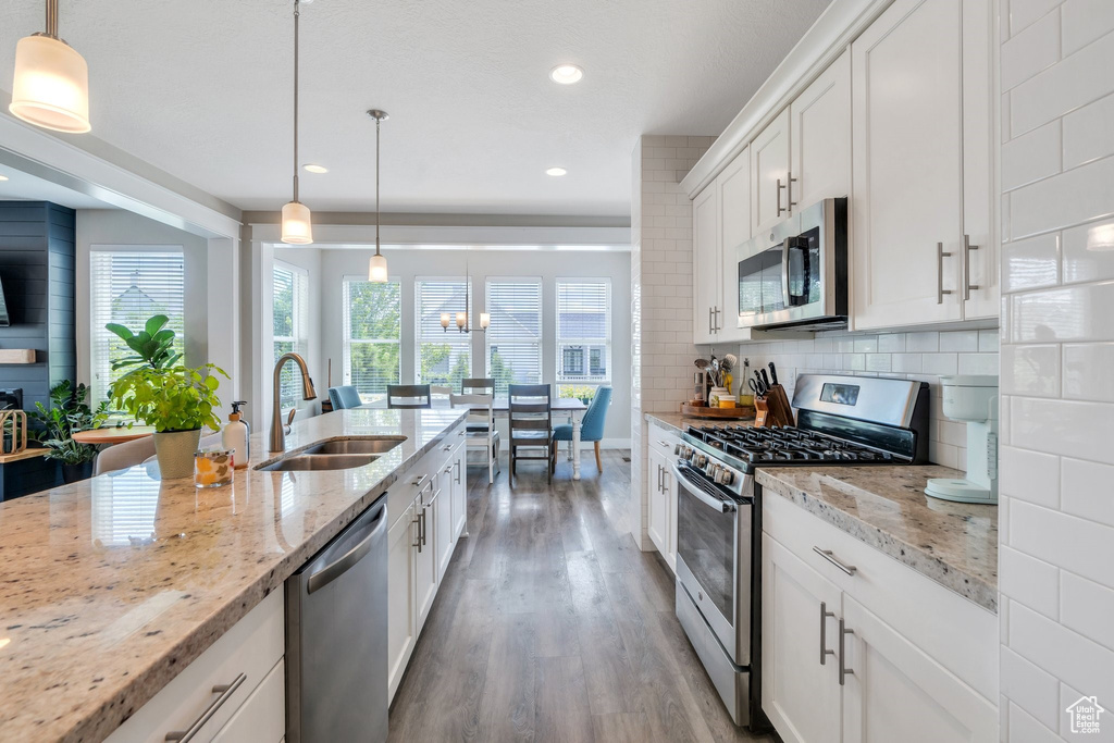 Kitchen featuring stainless steel appliances, wood finished floors, recessed lighting, white cabinets, and decorative backsplash