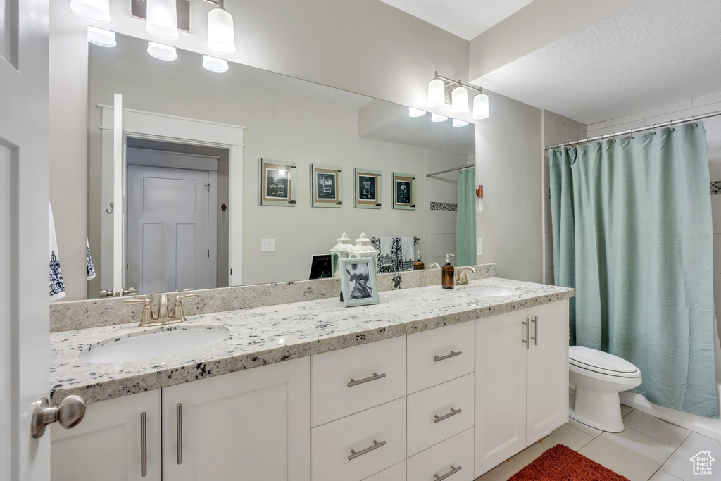 Full bathroom featuring double vanity, tile patterned flooring, and a shower with curtain
