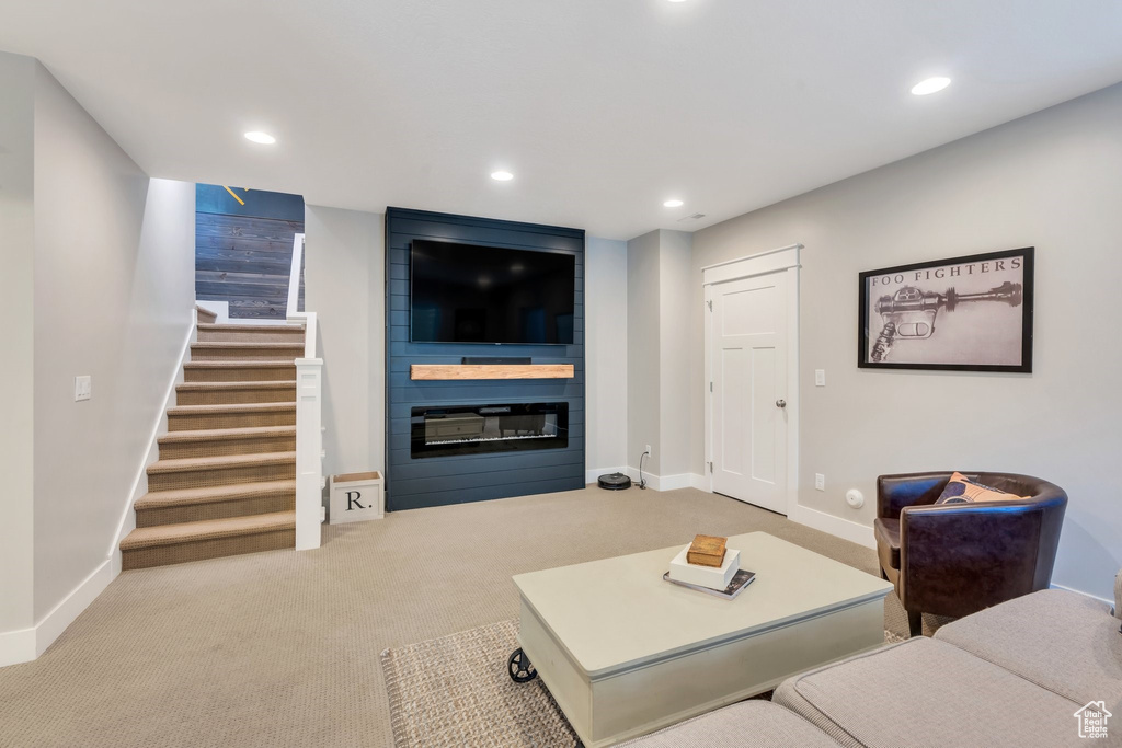 Living area with a large fireplace, stairs, recessed lighting, and carpet