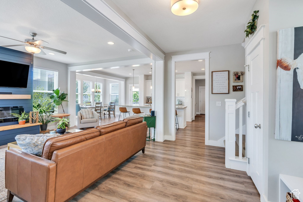 Living area with ceiling fan, light wood finished floors, a fireplace, and recessed lighting