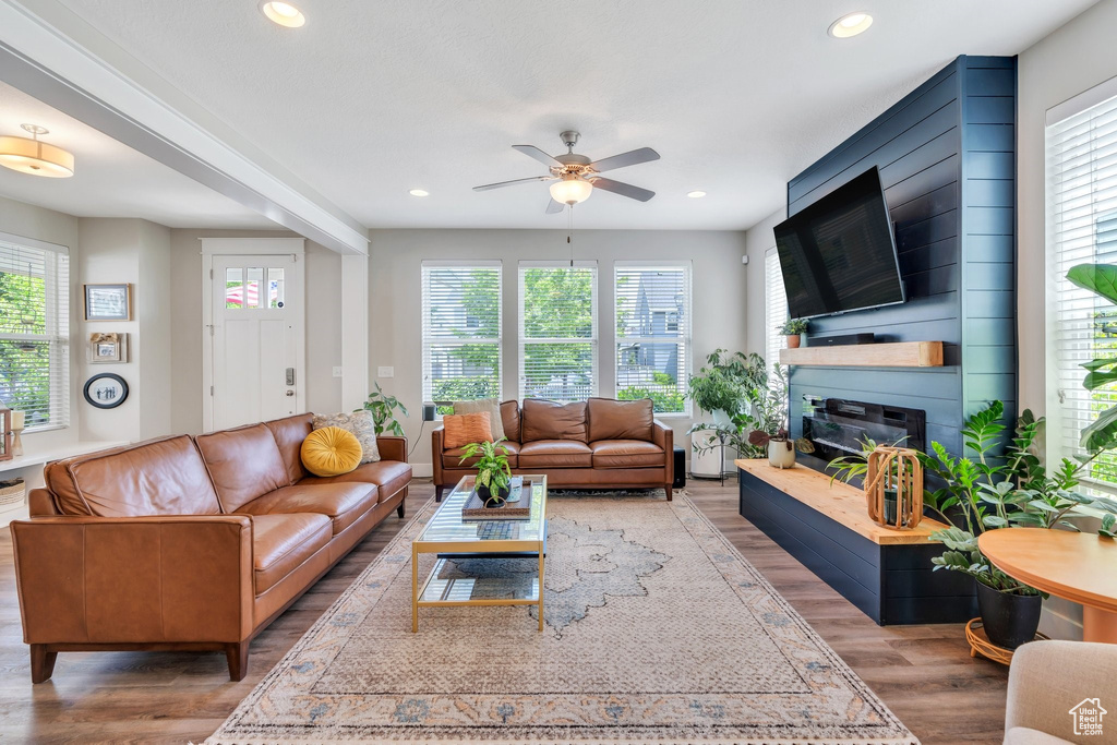 Living area featuring a ceiling fan, wood finished floors, a large fireplace, and recessed lighting