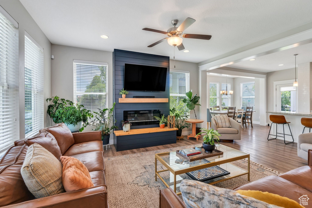 Living room with wood finished floors, a ceiling fan, a fireplace, and recessed lighting