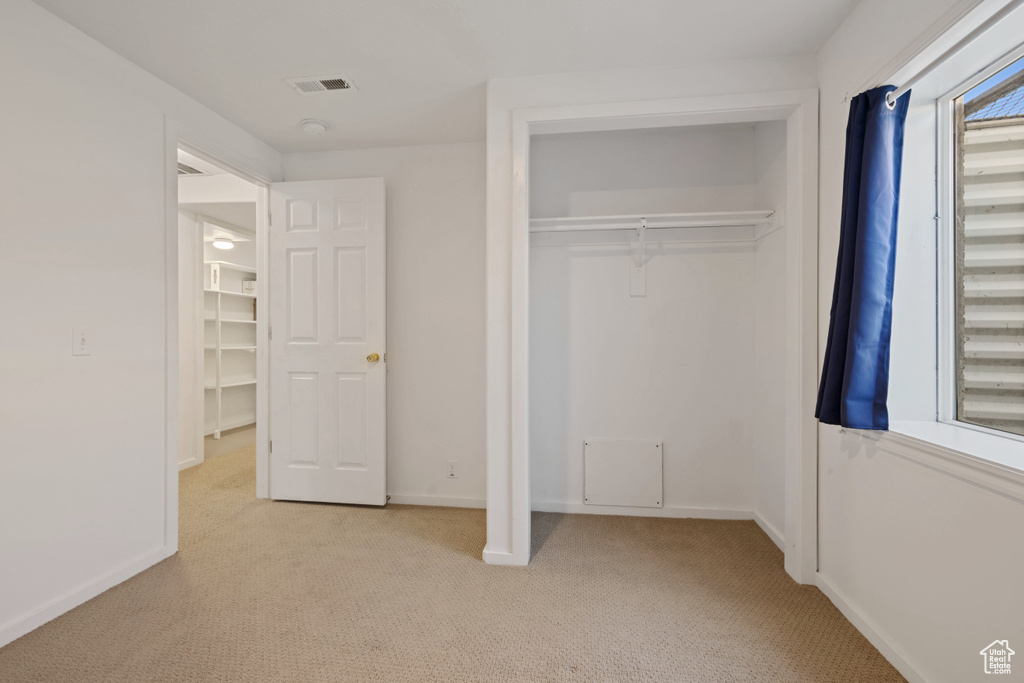 Unfurnished bedroom featuring light carpet and a closet