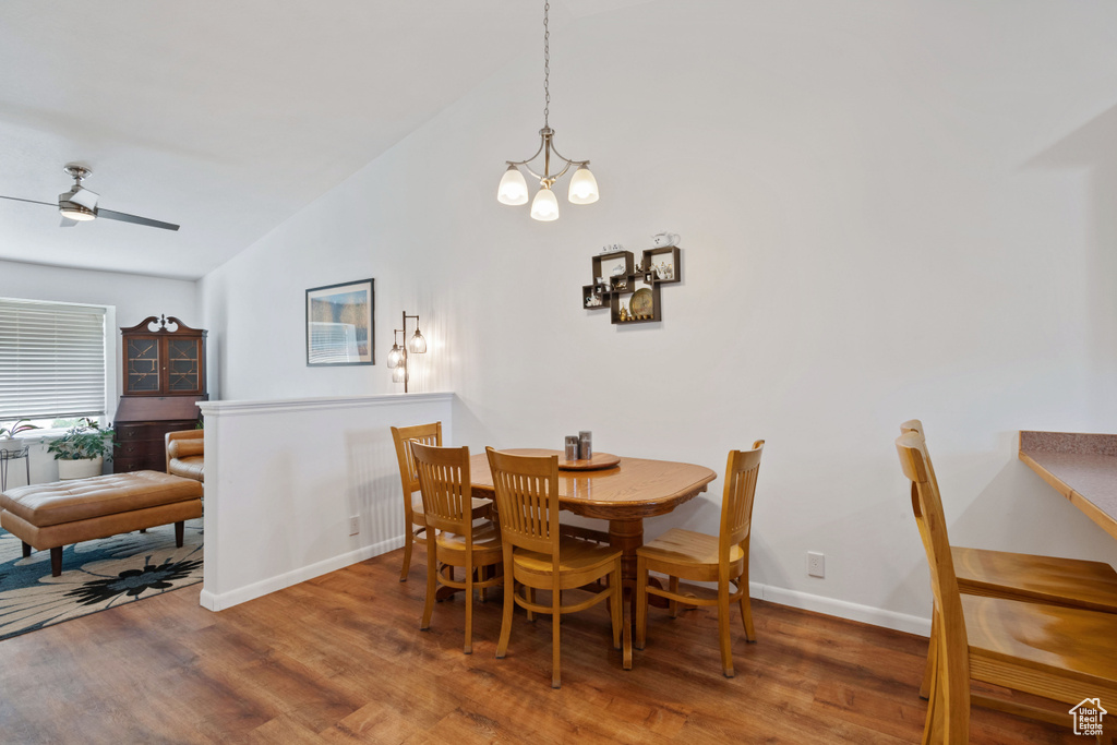 Dining room featuring vaulted ceiling, wood finished floors, a chandelier, and ceiling fan
