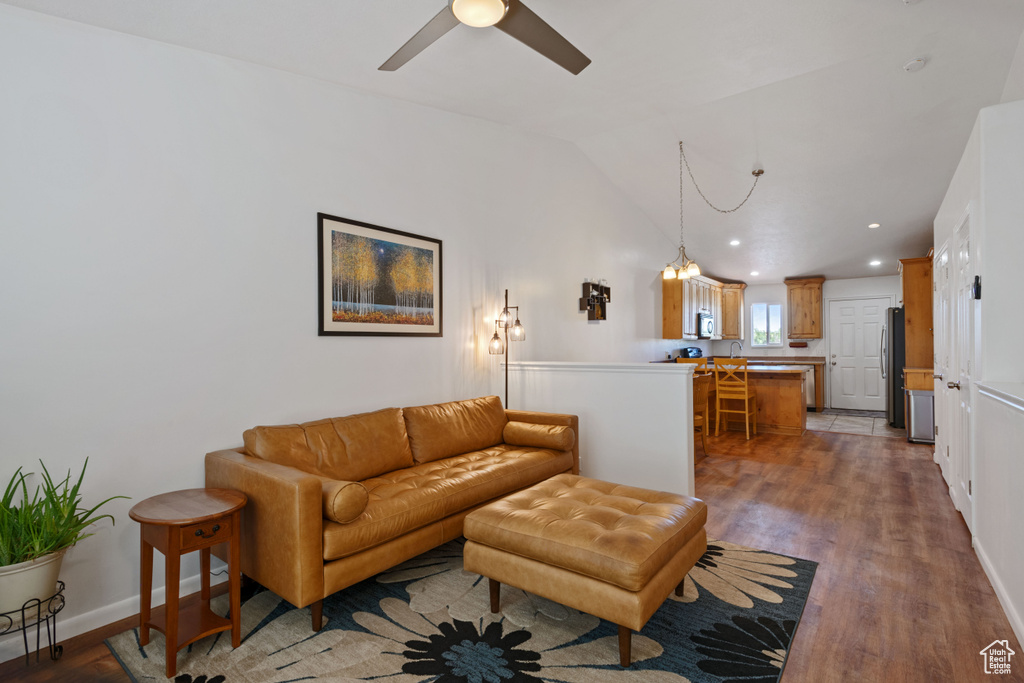 Living room with wood finished floors, lofted ceiling, recessed lighting, a ceiling fan, and a chandelier