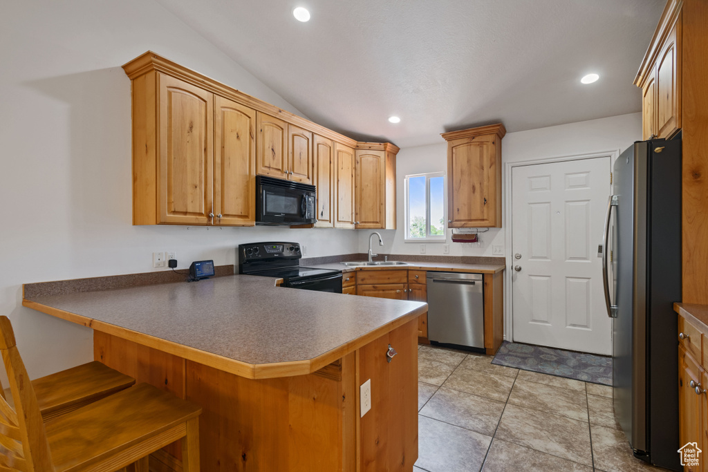 Kitchen featuring black appliances, a peninsula, a breakfast bar area, and recessed lighting