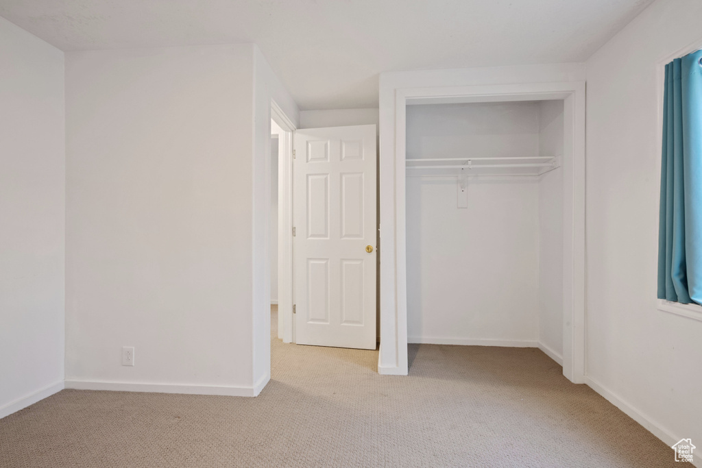 Unfurnished bedroom featuring light carpet and a closet