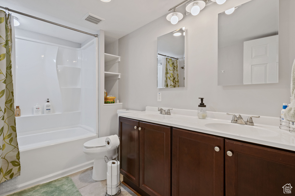 Full bathroom featuring double vanity, shower / tub combo, and tile patterned flooring