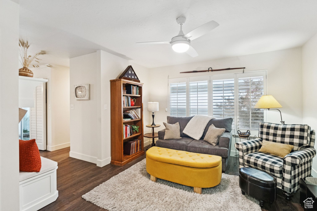Living room featuring dark wood finished floors, a ceiling fan, and baseboards