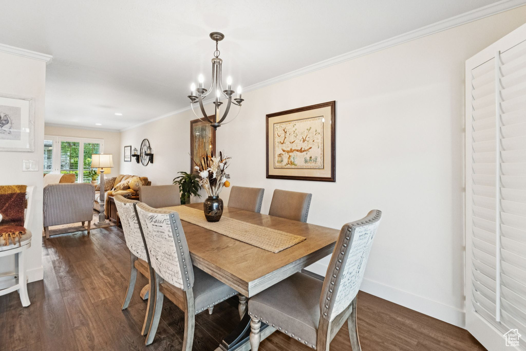 Dining space featuring a chandelier, dark wood finished floors, crown molding, and baseboards