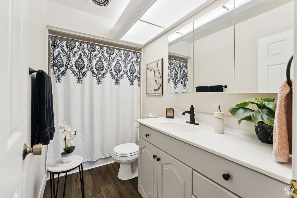 Bathroom featuring vanity, toilet, wood finished floors, and a shower with shower curtain