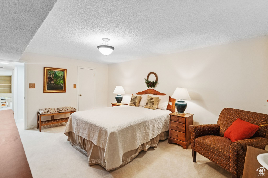 Bedroom with light colored carpet and a textured ceiling