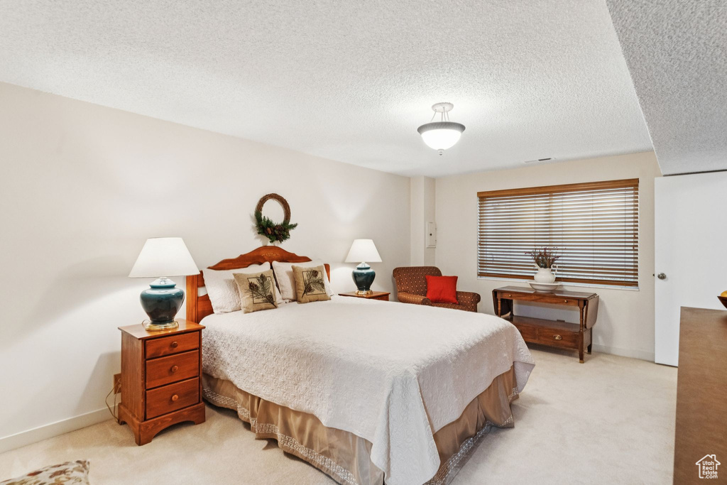 Bedroom with light colored carpet, a textured ceiling, and baseboards