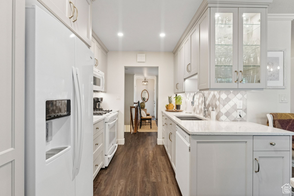 Kitchen with white appliances, a sink, dark wood-style flooring, glass insert cabinets, and backsplash