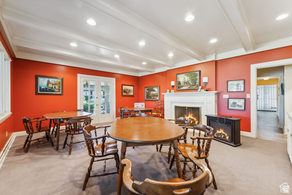 Dining area featuring a lit fireplace, carpet, french doors, beam ceiling, and recessed lighting
