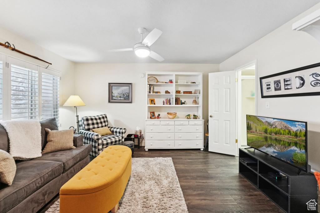 Living room with ceiling fan and dark wood-style flooring