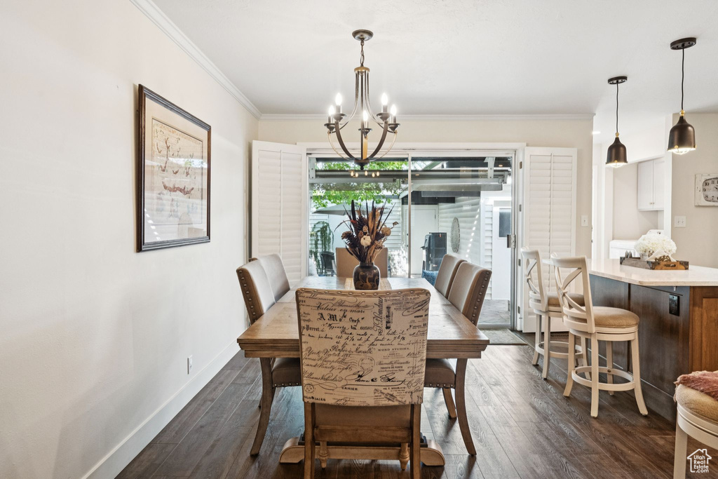 Dining space featuring a chandelier, dark wood-style floors, ornamental molding, and baseboards
