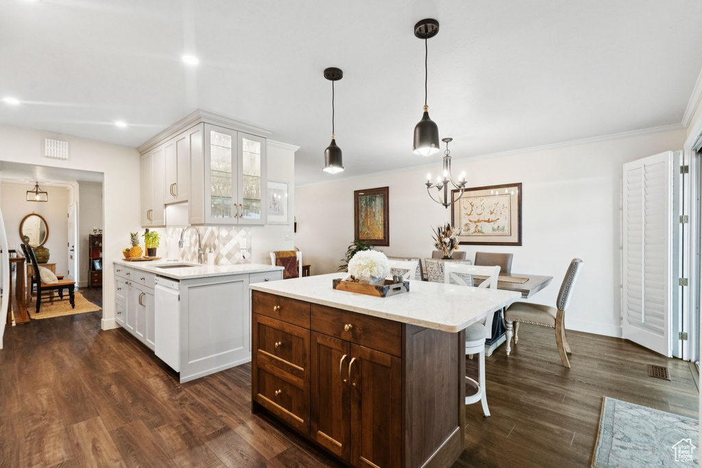 Kitchen featuring a kitchen bar, glass insert cabinets, white cabinets, a sink, and dark wood finished floors