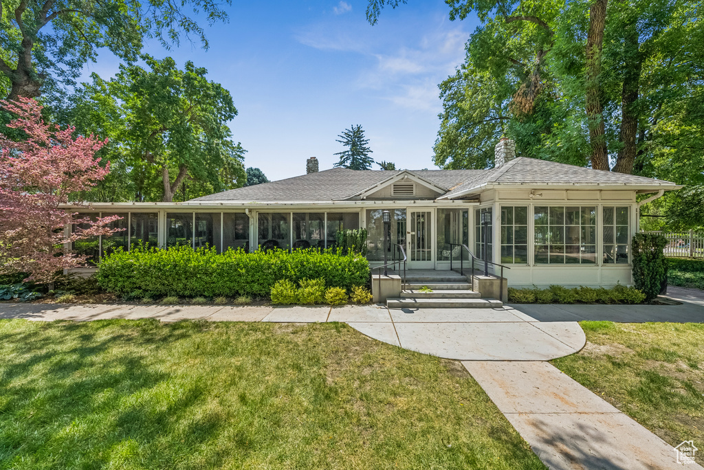 Rear view of house with a sunroom and a chimney