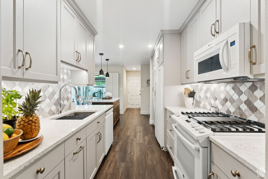 Kitchen featuring white appliances, a sink, dark wood finished floors, light stone countertops, and recessed lighting