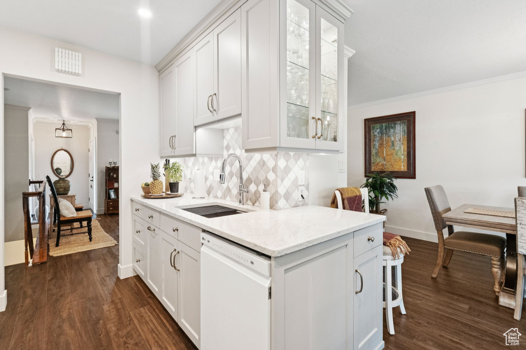 Kitchen featuring dishwasher, a sink, backsplash, dark wood-type flooring, and glass insert cabinets