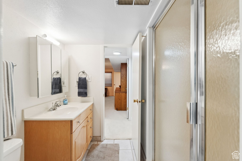 Bathroom with vanity, a shower stall, toilet, and tile patterned floors