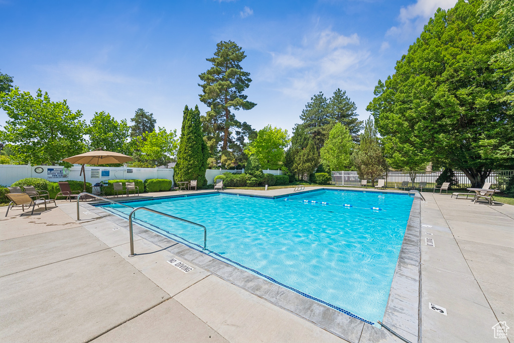 Community pool featuring a patio area and view of wooded area