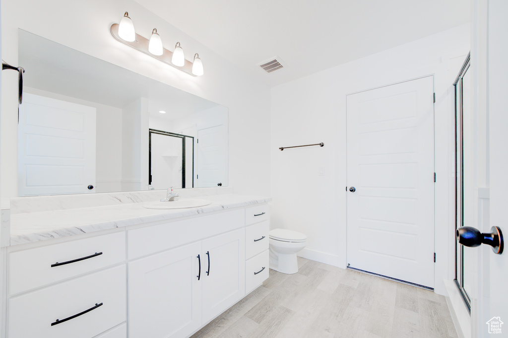 Bathroom with vanity, wood finished floors, and a shower with shower door