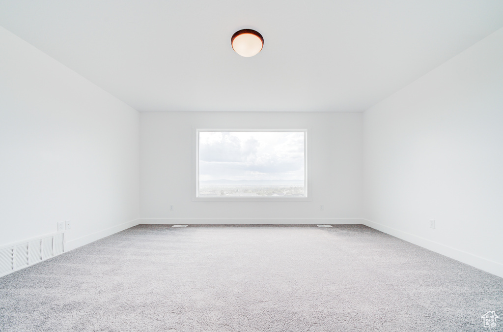 Carpeted spare room featuring baseboards