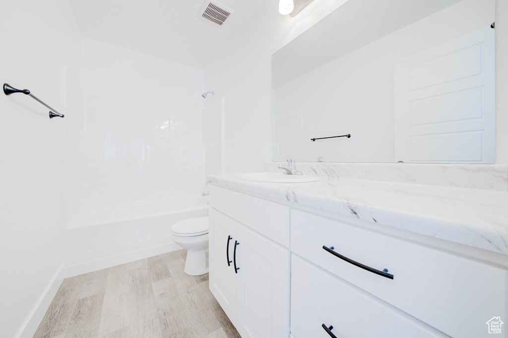 Bathroom with vanity, wood finished floors, and shower / tub combination