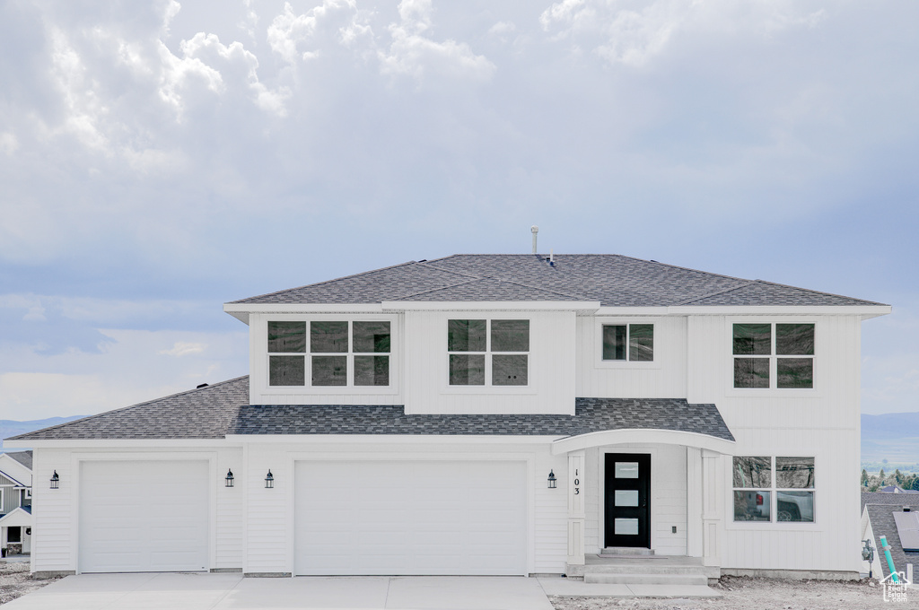 View of front of property with a shingled roof, concrete driveway, and a garage