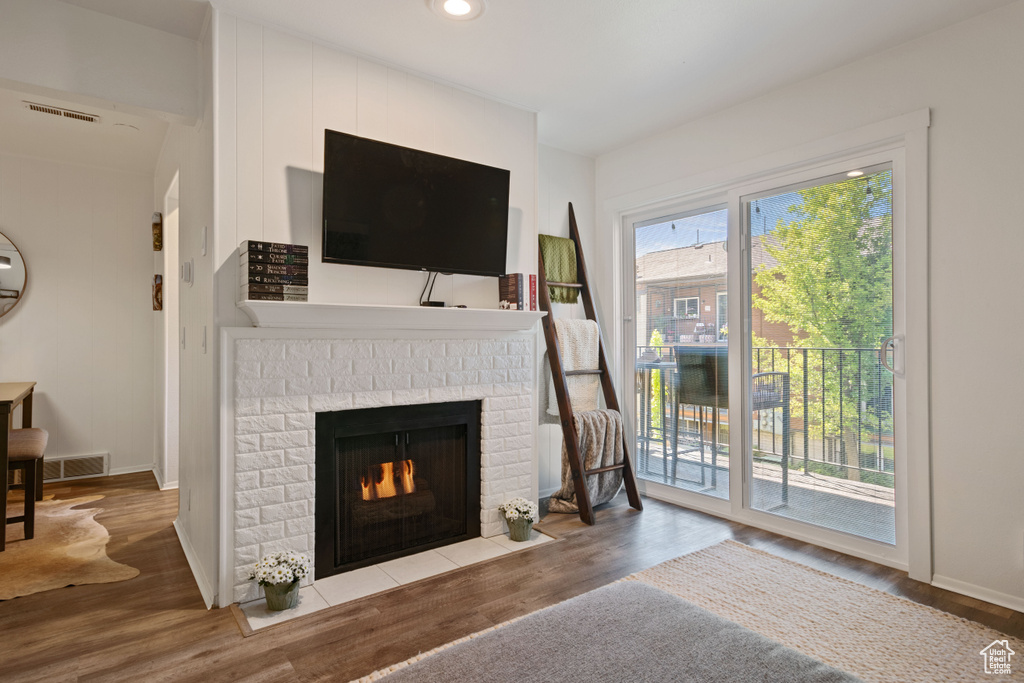 Living room with wood finished floors, a fireplace, and recessed lighting
