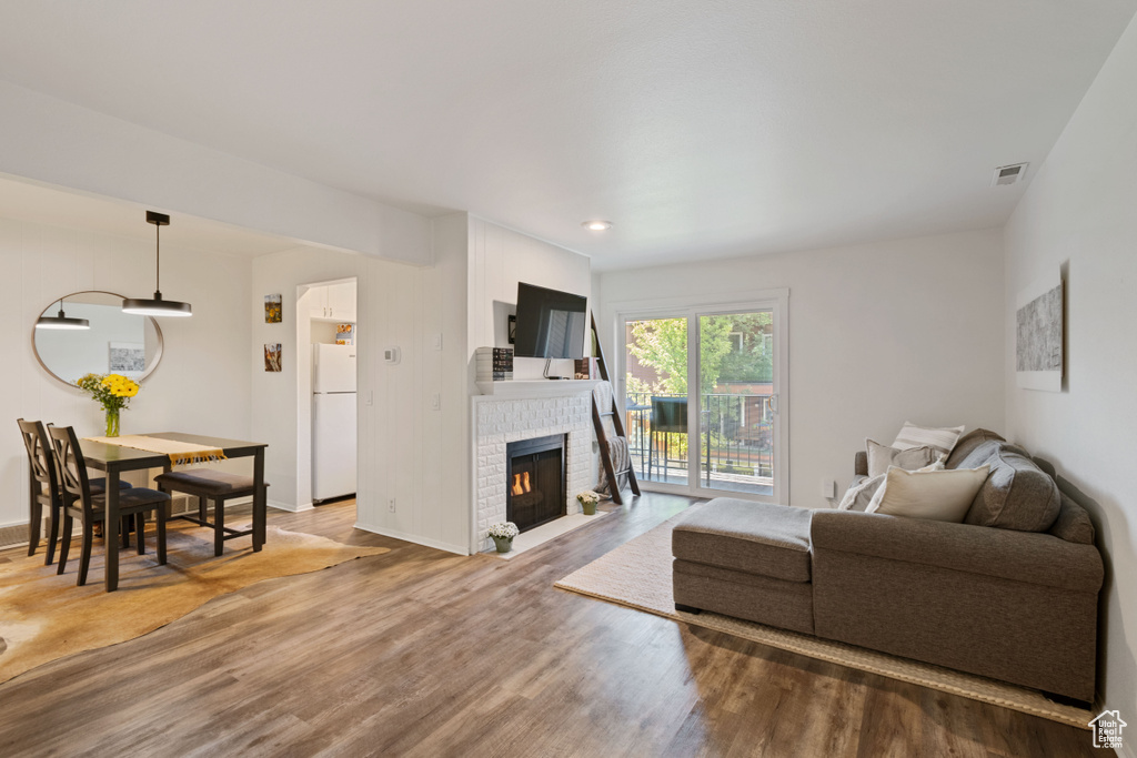 Living area with wood finished floors, a brick fireplace, and recessed lighting