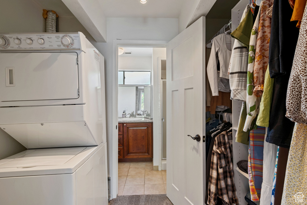 Laundry room with estacked washer and dryer and light tile patterned floors