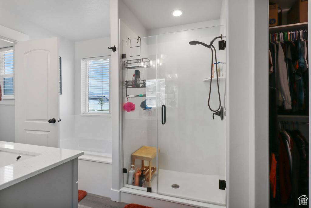 Bathroom with a shower stall, vanity, a walk in closet, a garden tub, and recessed lighting