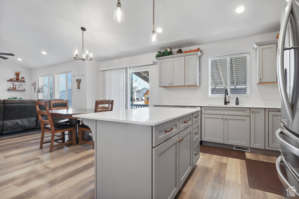 Kitchen with gray cabinets, freestanding refrigerator, light countertops, open floor plan, and wood finished floors
