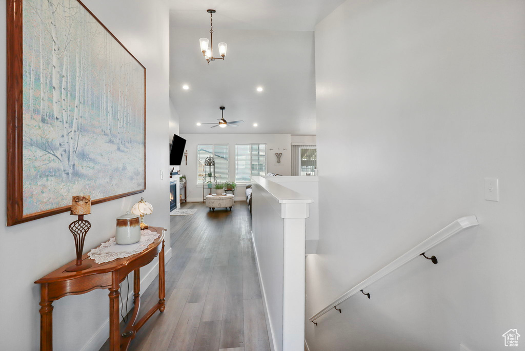 Hall with an upstairs landing, recessed lighting, wood finished floors, and a chandelier