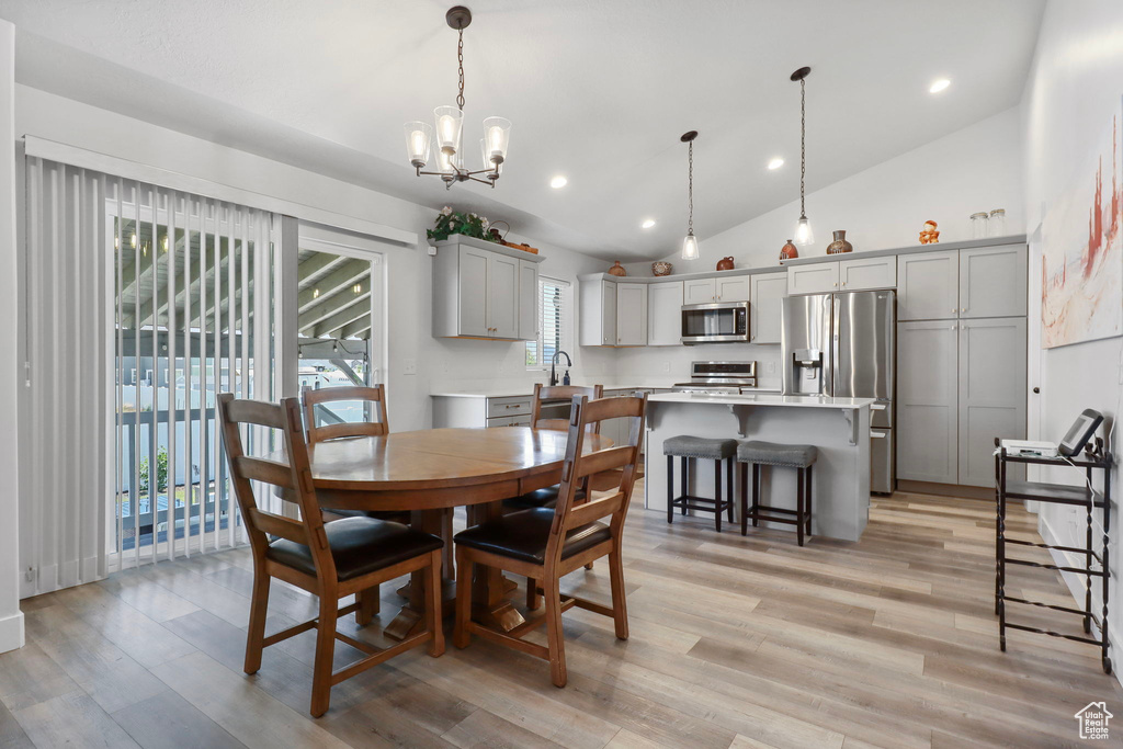 Dining area featuring lofted ceiling, healthy amount of natural light, recessed lighting, light wood-style flooring, and a chandelier