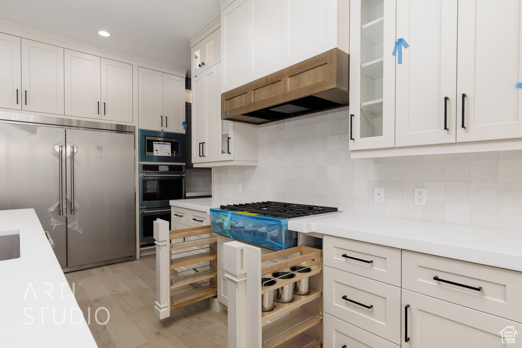 Kitchen featuring high quality fridge, light countertops, light wood-style flooring, white cabinets, and recessed lighting