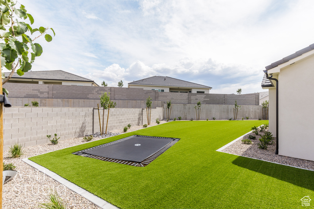 Fenced backyard featuring a trampoline