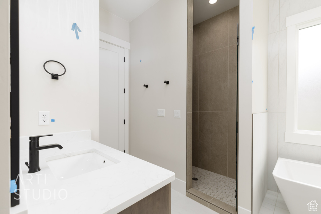 Bathroom with a soaking tub, a tile shower, and vanity