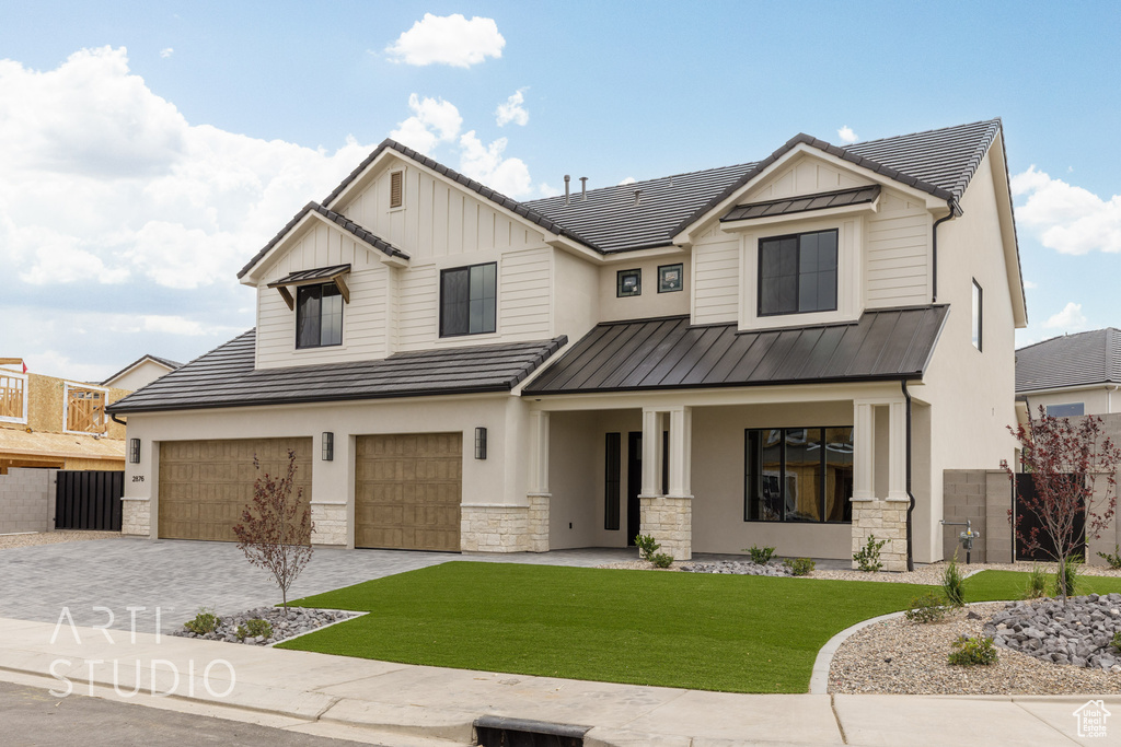 Modern farmhouse style home featuring stone siding, a standing seam roof, covered porch, an attached garage, and decorative driveway