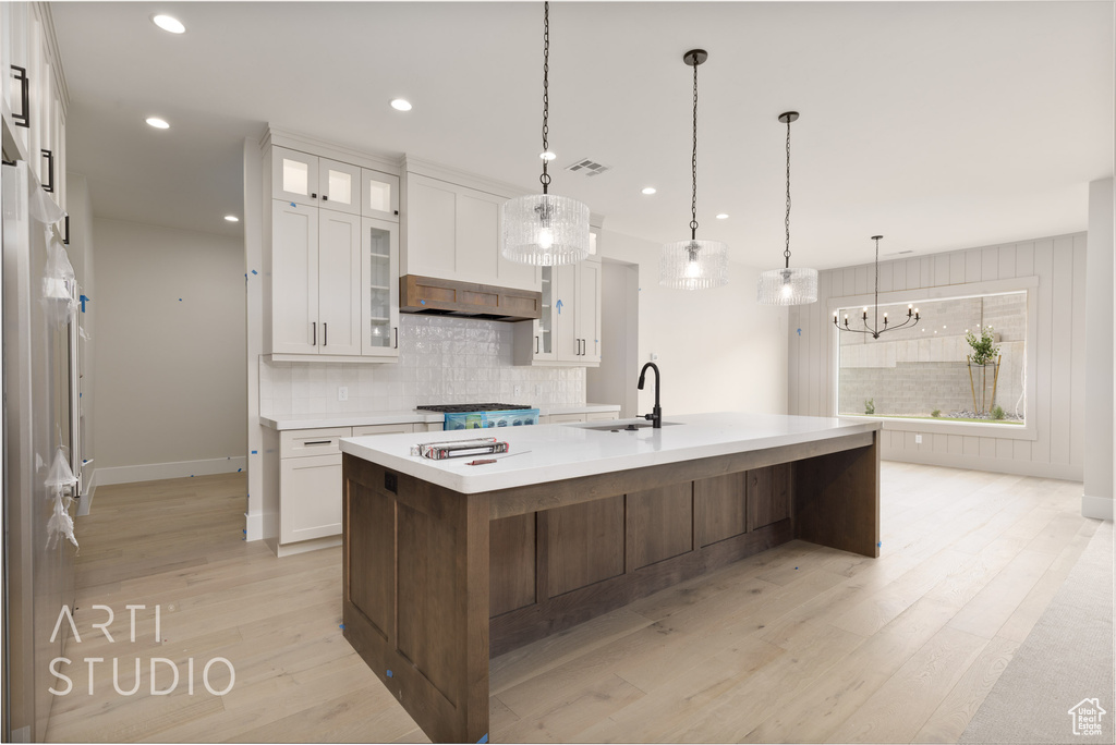 Kitchen featuring a sink, tasteful backsplash, white cabinetry, light countertops, and recessed lighting