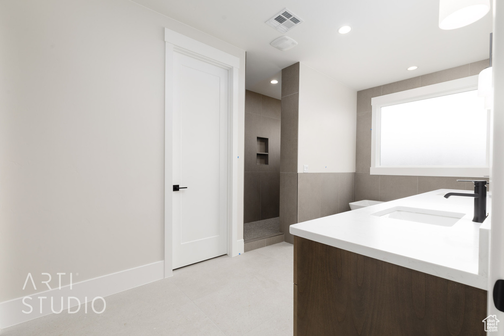 Bathroom featuring double vanity, recessed lighting, and a tile shower
