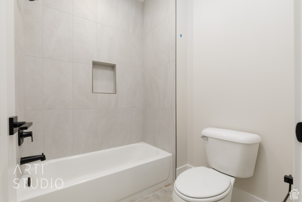 Bathroom featuring toilet, baseboards, and  shower combination