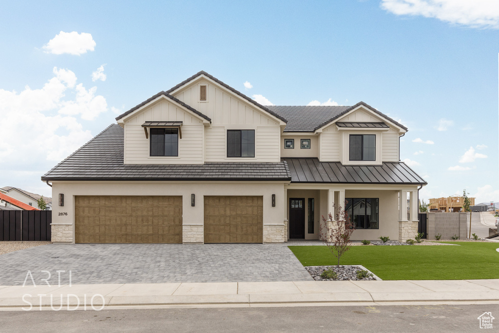 View of front of house featuring stone siding, an attached garage, decorative driveway, and a standing seam roof