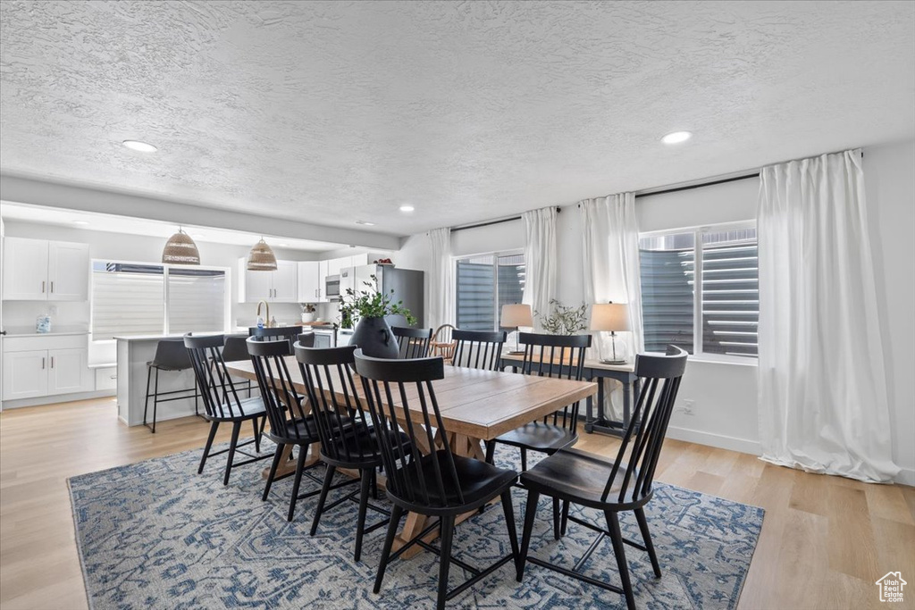 Dining room featuring a textured ceiling, light wood-type flooring, and recessed lighting