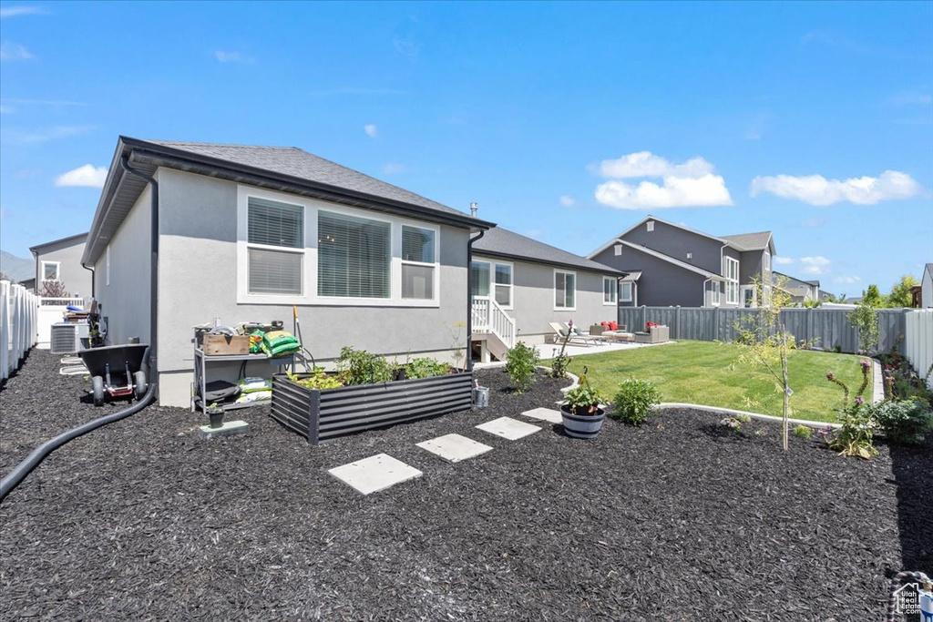 Back of house featuring a fenced backyard, stucco siding, a patio area, a vegetable garden, and a residential view